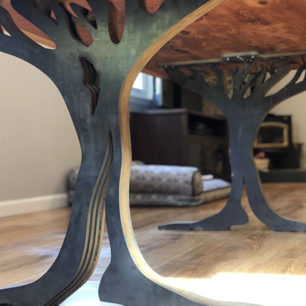 Close view of a steel table base cut in the shape of a tree, under a wood top