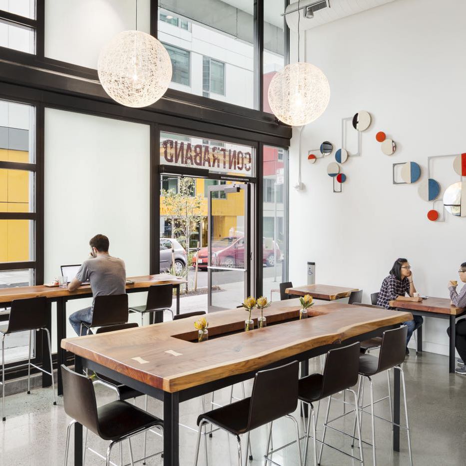 Café with live edge counters and communal tables on black steel bases