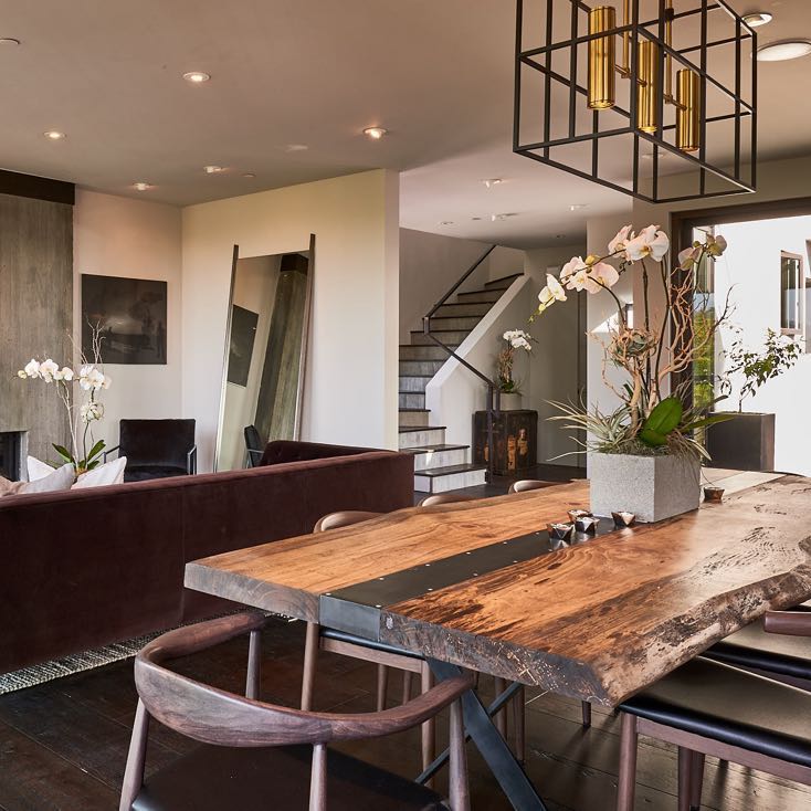 Live edge dining table with a steel band across the top, in an open living and dining room