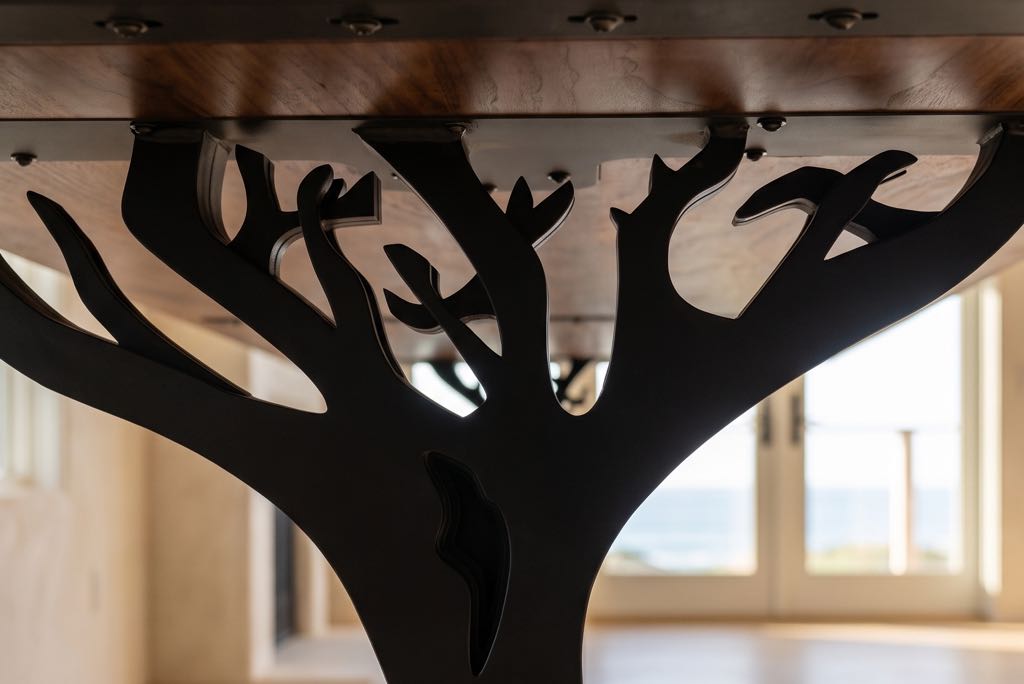 The steel branches of one leg reaching up to the underside of the walnut top
