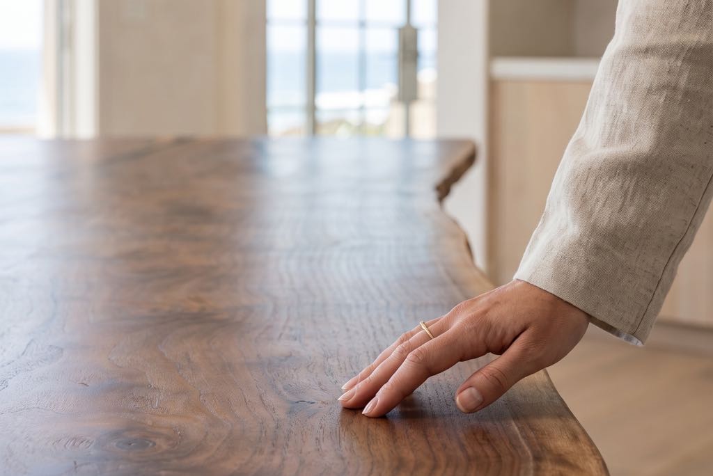A hand resting on the square-cut end of the live-edge walnut top