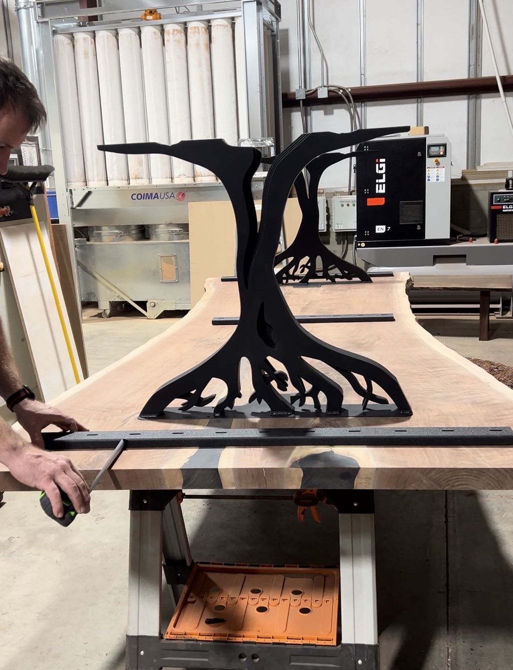 The table upside down on the bench during assembly, with a tree leg fitted to the underside of the top
