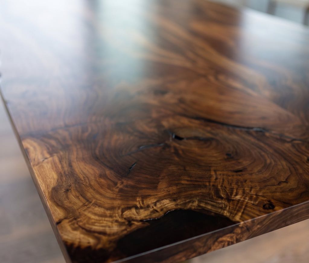 Swirling chocolate and caramel figure around a small natural void at the dark end of the walnut top