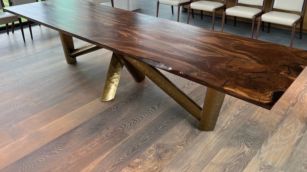 The real orchard walnut table in the client's home: a long figured walnut top on hammered metal legs, on a wide-plank oak floor