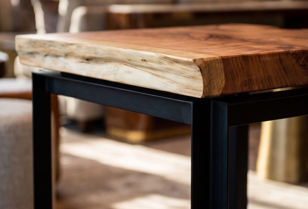 Corner of a café table: the thick redwood top resting on its black steel frame, with an angle-iron leg below