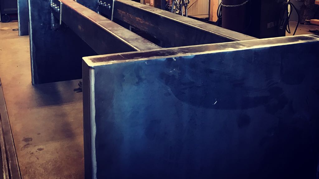 The steel base in our shop before finish: wide plate legs joined by two long box beams