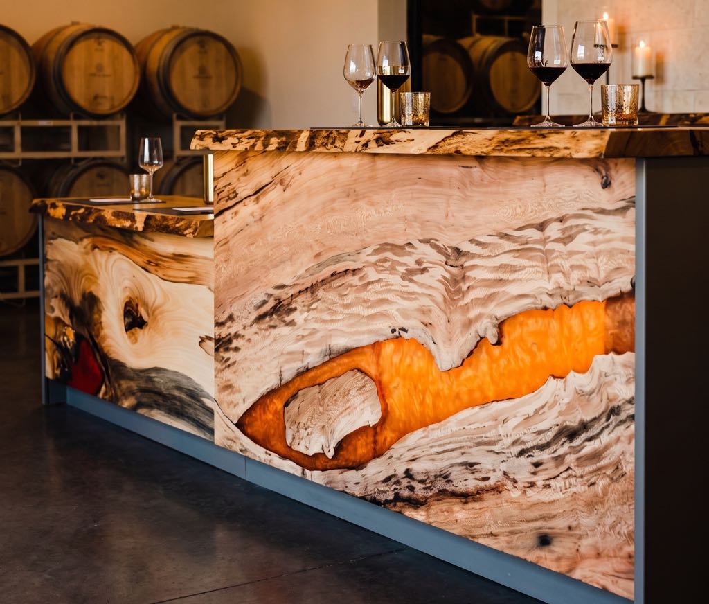The sycamore bar at dusk in a styled tasting room, its orange resin river glowing from behind