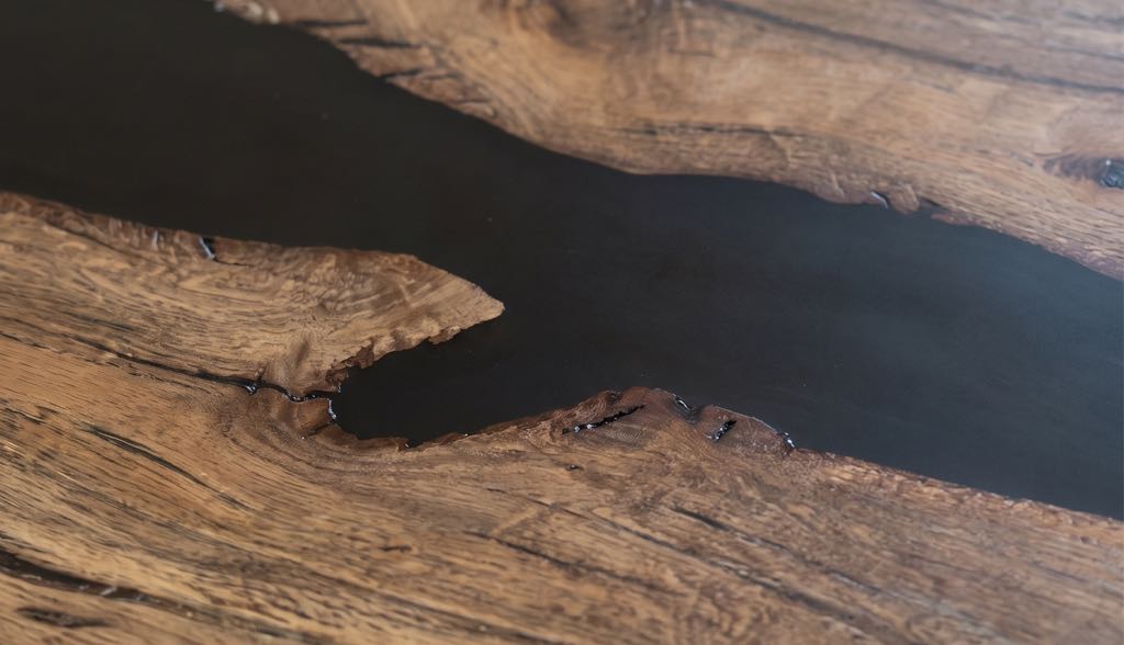 Close-up of the jagged live edges of the oak meeting the black resin river