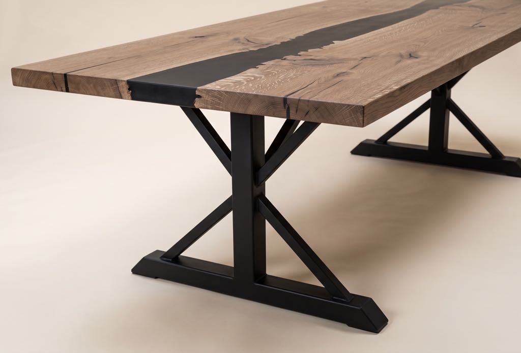 One of the black steel trestles under the oak top: a center post, an angled foot and four braces forming an X