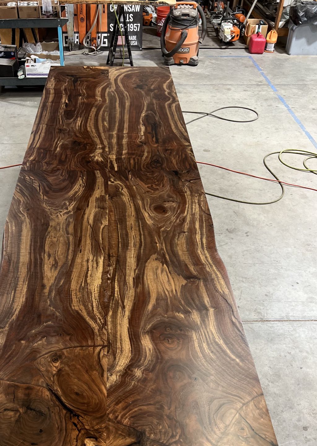 The finished orchard walnut top on sawhorses in our shop, four slabs joined into one long top before the base went on