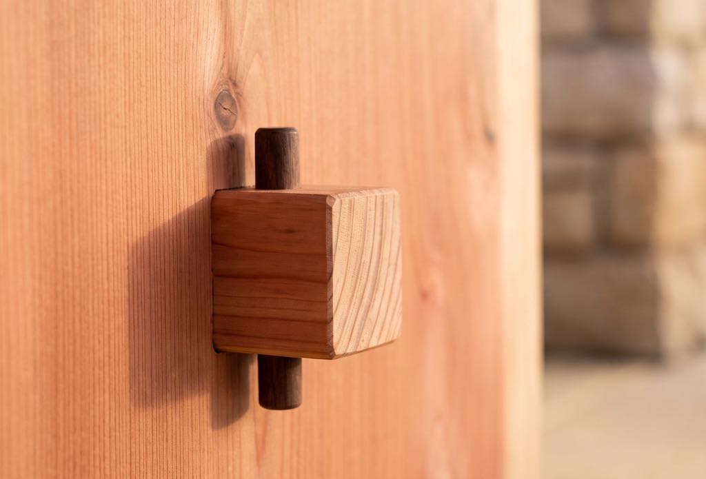 Close-up of the square wooden key with a dark pin, locking the through tenon on the outside of a redwood leg