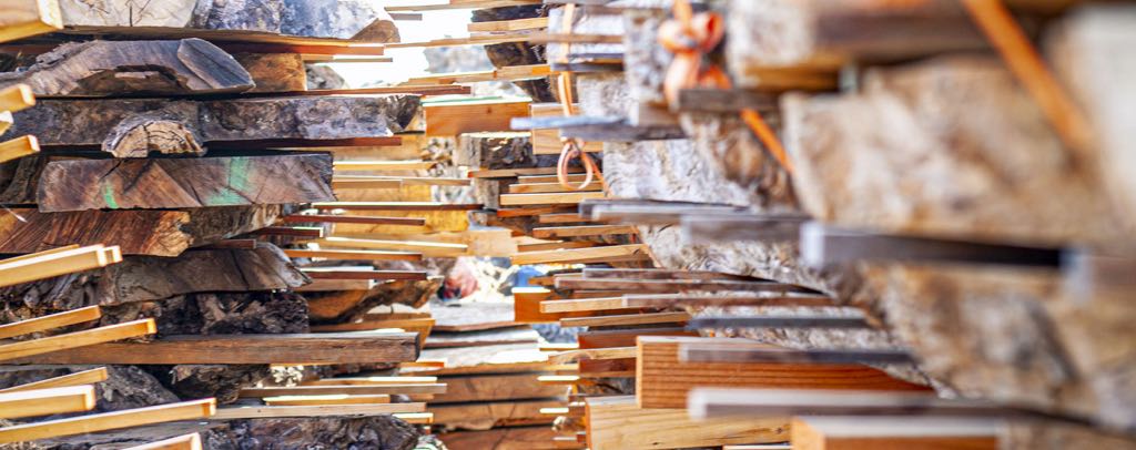 Rows of fresh-cut slabs stacked with thin sticks between them so air can move through while they dry